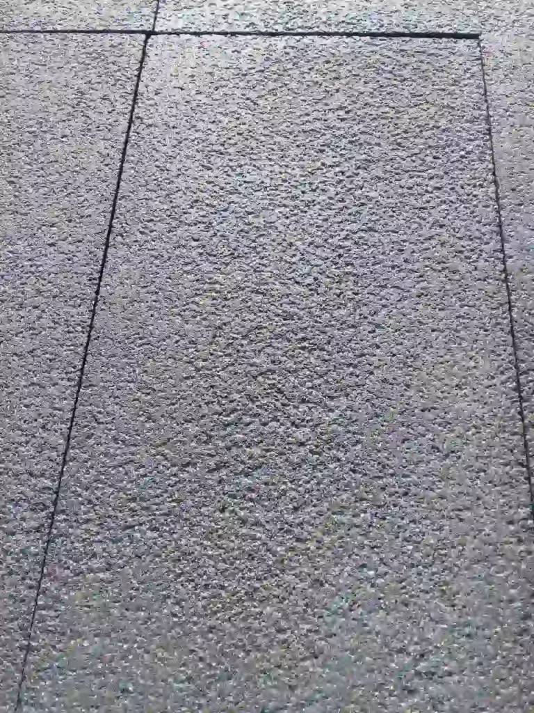 Close-up of a bush-hammered basalt stone surface, highlighting the small, rough indentations and volcanic texture.