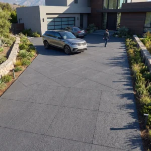 Large-format natural stone pavers with a textured finish forming a geometric driveway leading to a modern home