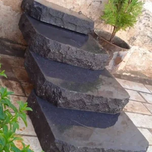 Natural black basalt garden stepping stones set into a lawn for a low-maintenance walking path.