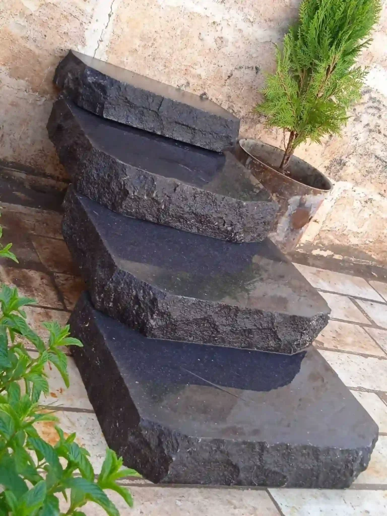 Natural black basalt garden stepping stones set into a lawn for a low-maintenance walking path.
