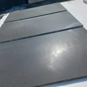 Large format polished basalt floor tiles installed on a luxury covered outdoor terrace or patio.