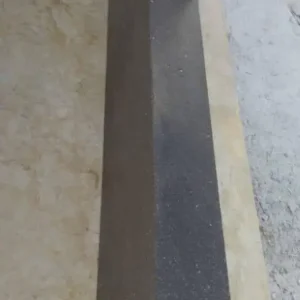 Thick natural stone landscape curbing used to create a clean, defined border between a driveway and a garden.