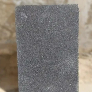 Close-up detail of natural sawn basalt texture showing subtle diamond-blade striations and volcanic mineral highlights