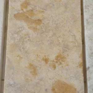 Tumbled yellow limestone flooring with soft, rounded edges and a weathered, antique surface for a rustic interior.