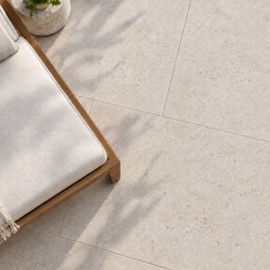 Large-format white limestone patio pavers beside a wood-framed lounger with dappled leaf shadows