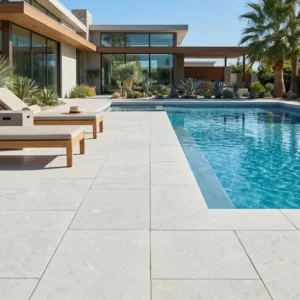 White Limestone Polished 24x12 pavers surrounding a pool with wood lounge chairs, framed by palm trees and desert landscaping at a modern home
