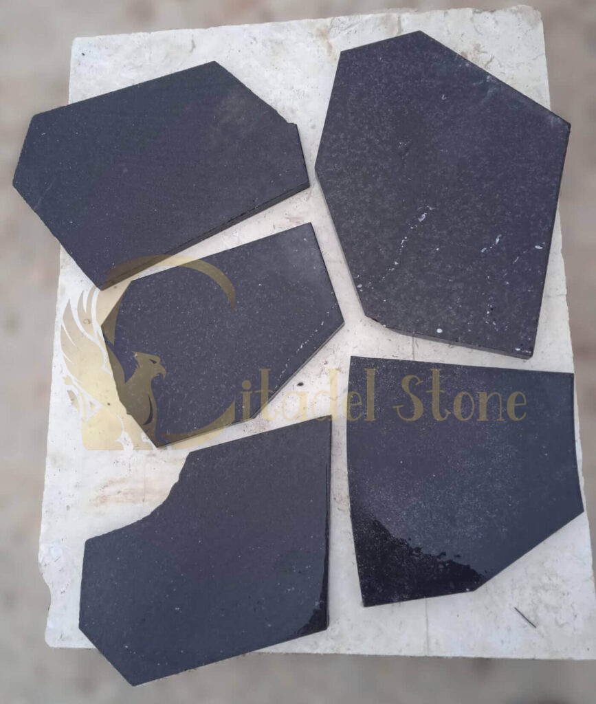 Installation process of black basalt tiles on a surface.