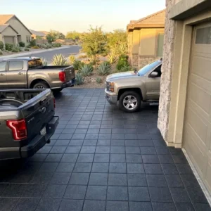 Dark charcoal square stamped paver driveway outside a suburban home with pickup trucks parked alongside it.