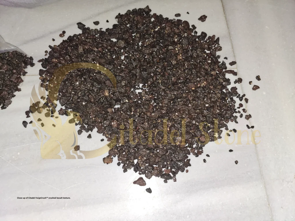 Close-up view of angular dark grey crushed basalt aggregate particles in sample bag