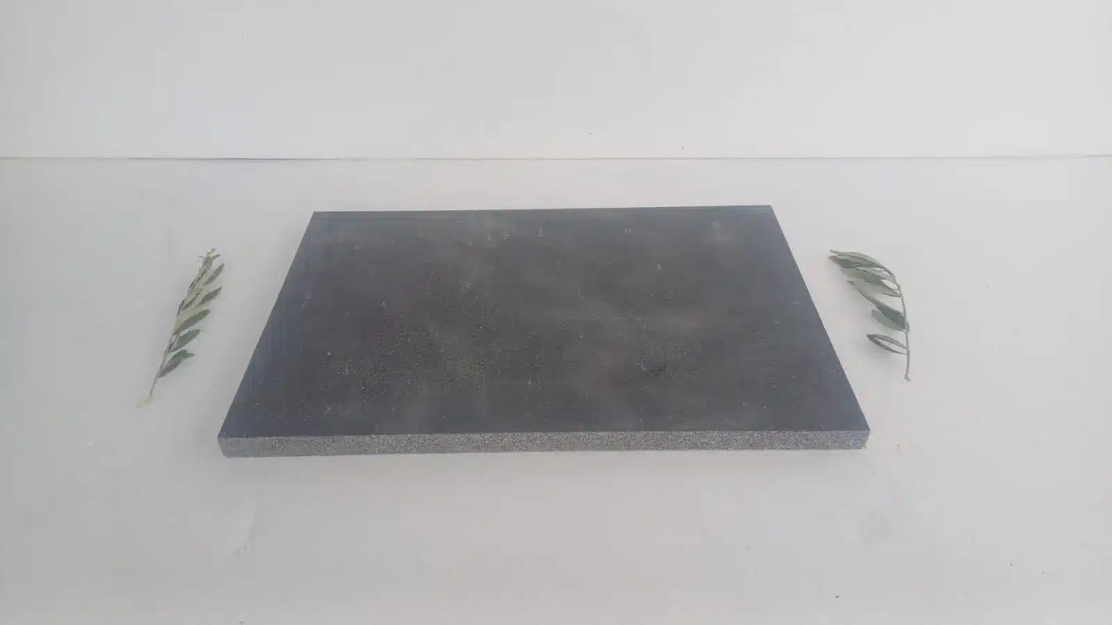 A dark stone slab surrounded by greenery focused on stone yard etiquette Arizona buyers.-img2