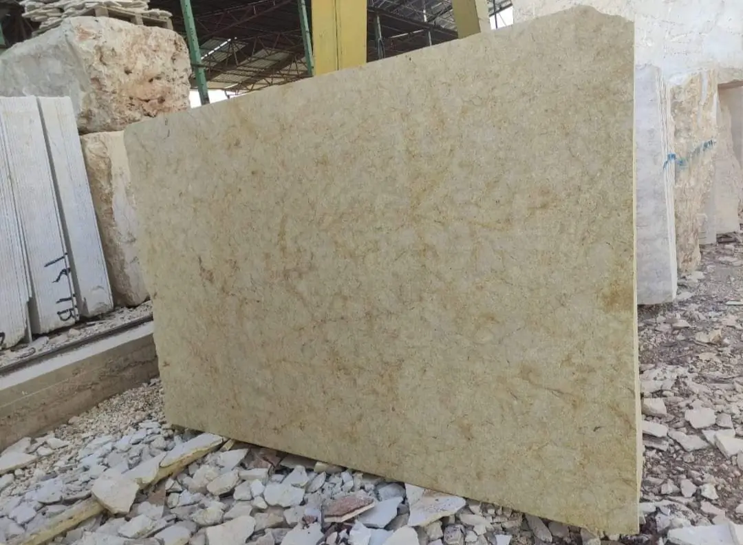 Close-up view of a large, light beige marble slab with subtle veining.
