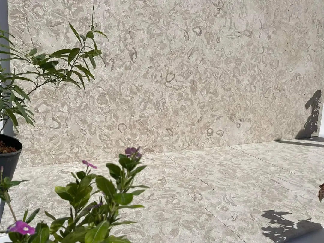 A large, textured natural stone slab rests against matching floor tiles.