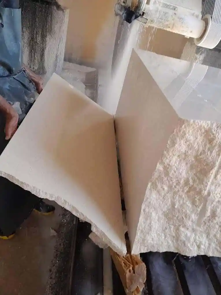 A powerful saw cuts through a large, light-colored stone block.