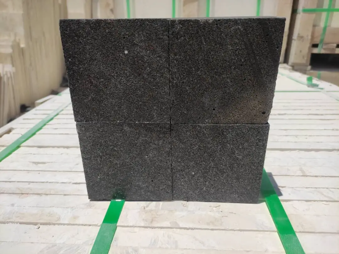 Close-up view of four dark, speckled stone blocks stacked together.