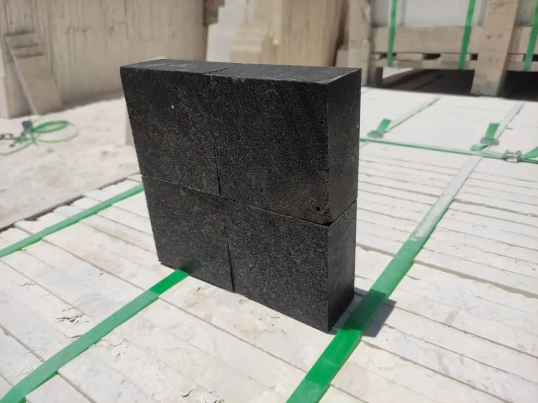 Two stacked dark granite blocks, divided by lines, secured with green straps.