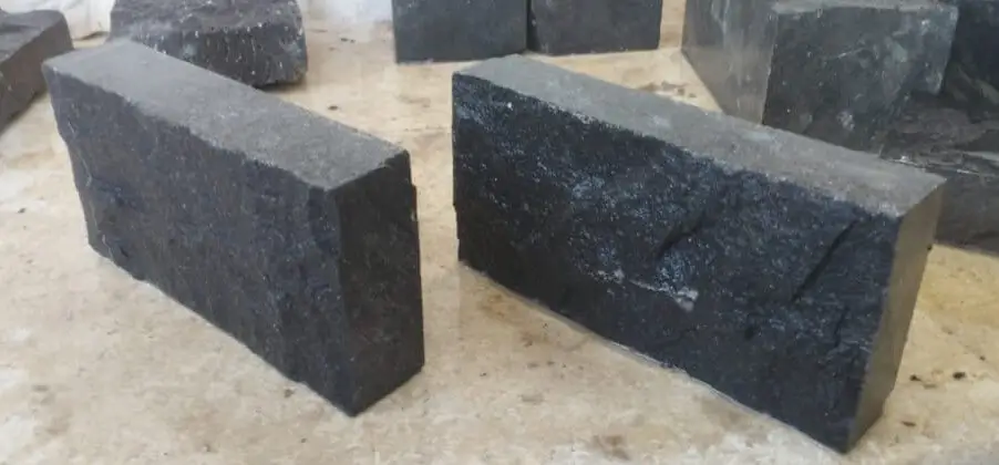 Two dark, rough-cut basalt blocks lie on a light surface.