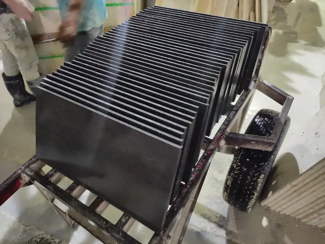 Dark, smooth stone slabs stacked neatly on a metal cart.