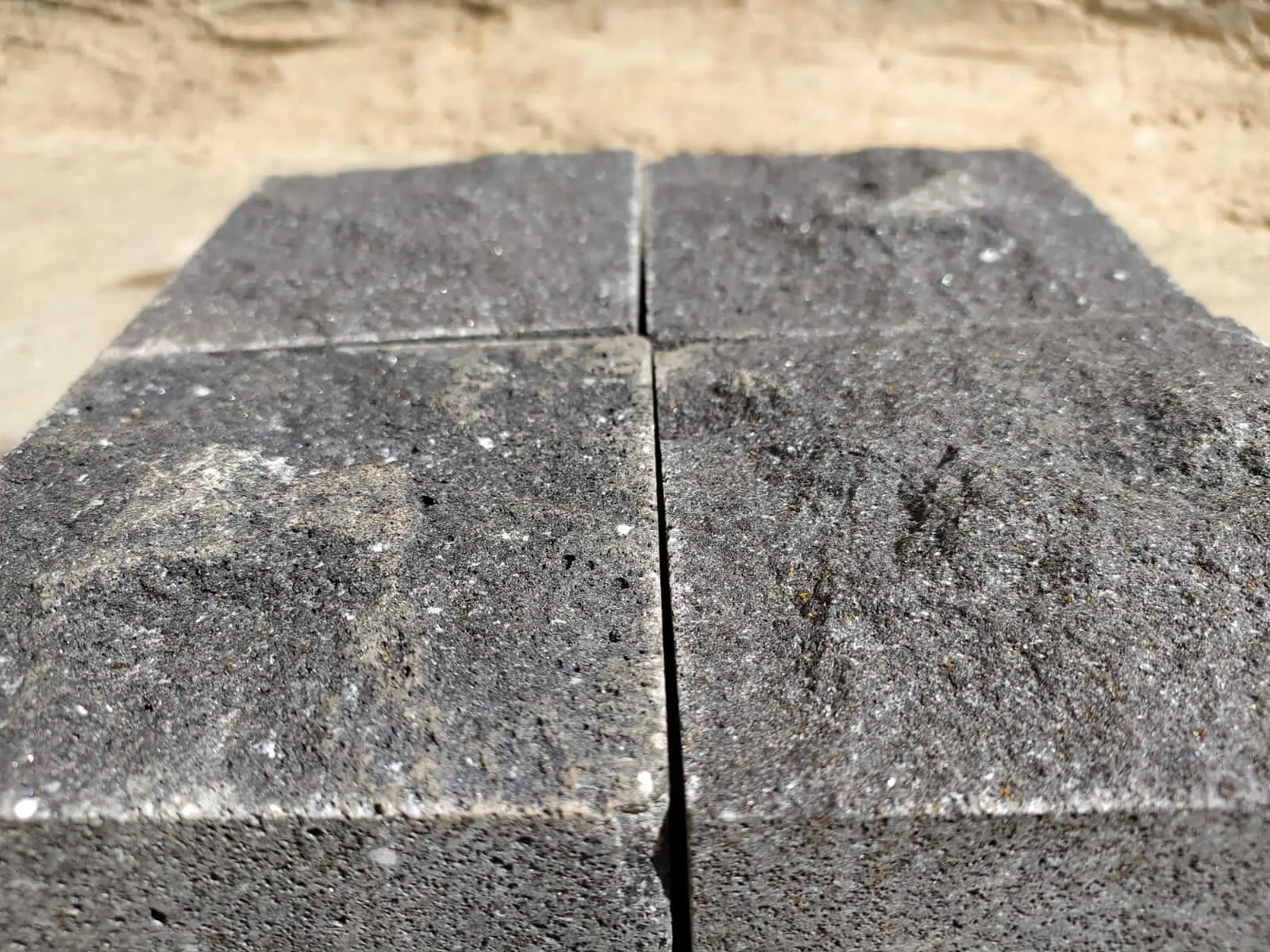 Close-up view of four dark, textured basalt pavers joined together.