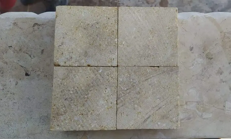 Four square textured sandstone tiles arranged together on a surface.