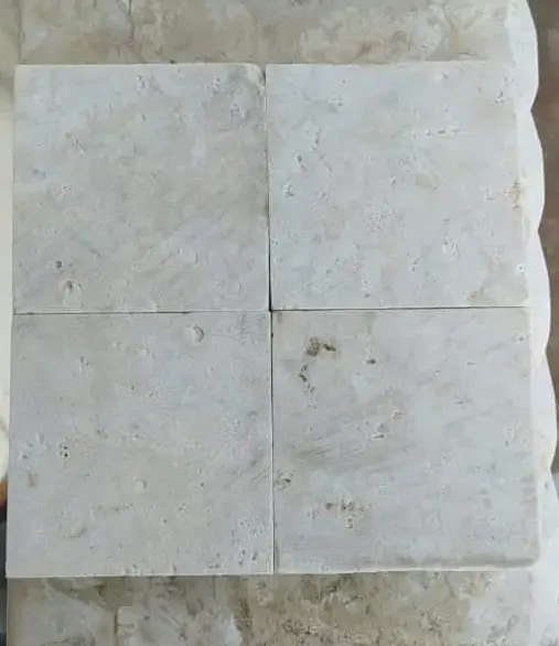 Four square travertine tiles with textured natural stone surfaces.