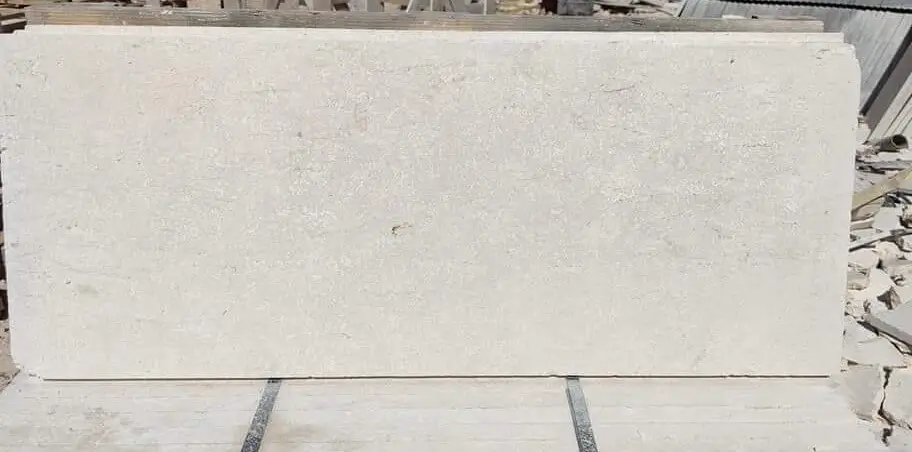 A large, rectangular, light-colored stone slab lies horizontally on a surface.