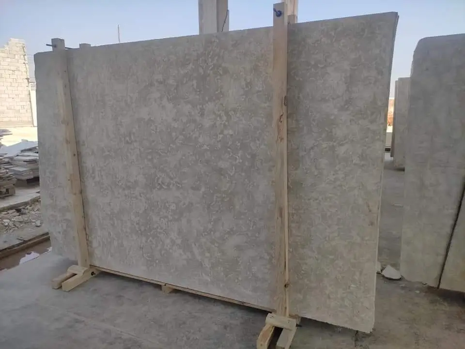 Several large, light-colored natural stone slabs are propped up