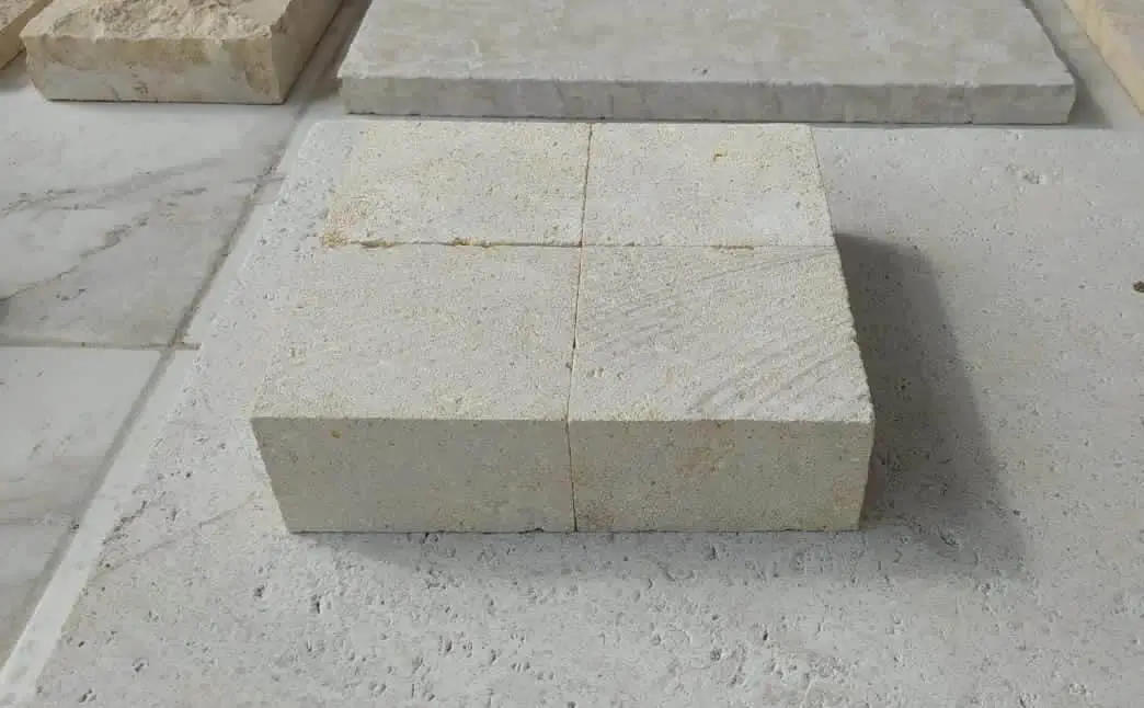 Four light colored square sandstone blocks are arranged on a larger stone surface.