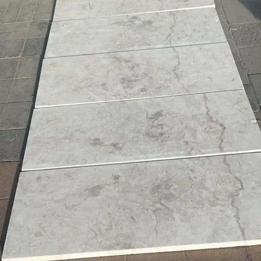 Rows of light grey limestone pavers with subtle veining are arranged on a sidewalk.