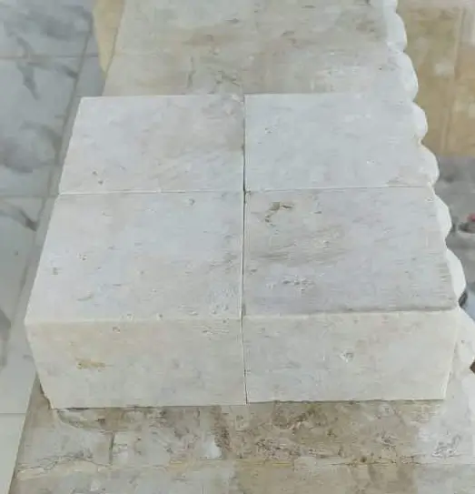 Light Stone Blocks Arranged Four light-colored, rectangular stone blocks are stacked on a textured surface.