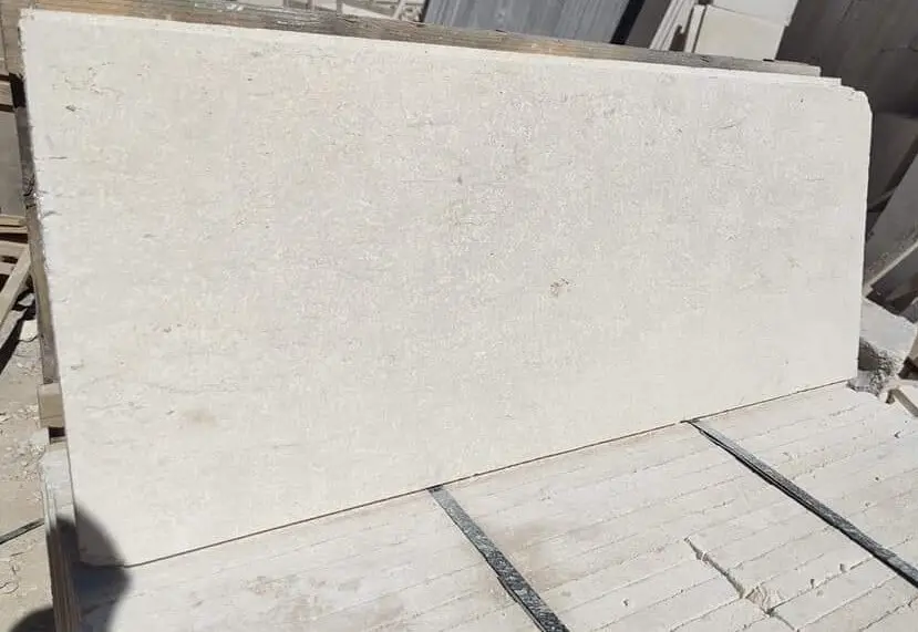 A pale beige stone slab rests on stacked material with metal straps.