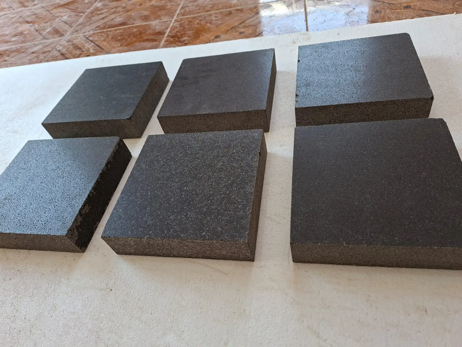 Six dark, speckled stone cubes arranged on a light surface.