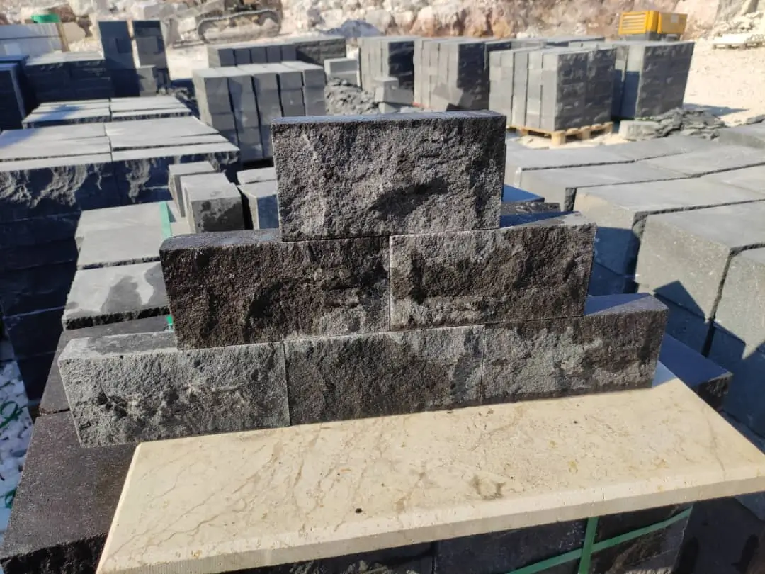 Several dark, rough-textured stone blocks are stacked in piles.