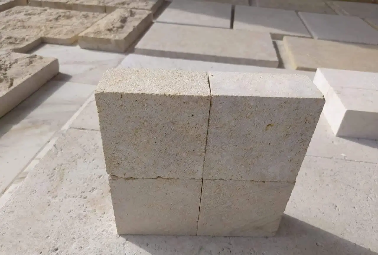 Close-up view of stacked light-colored rough-textured limestone blocks.