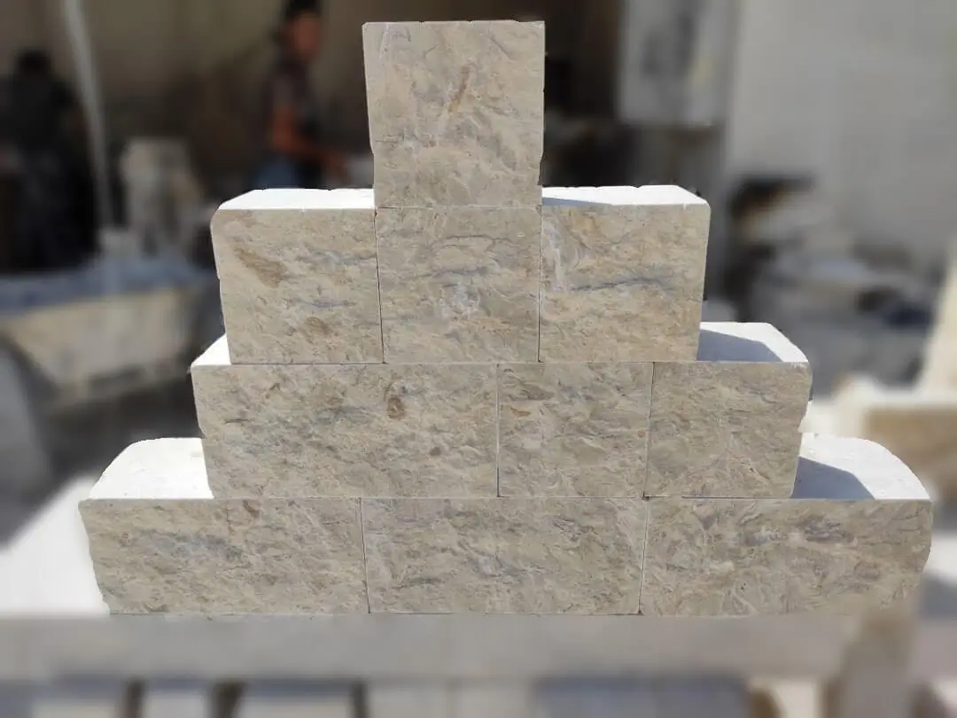 Light beige stone blocks stacked in pyramid formation outdoors.