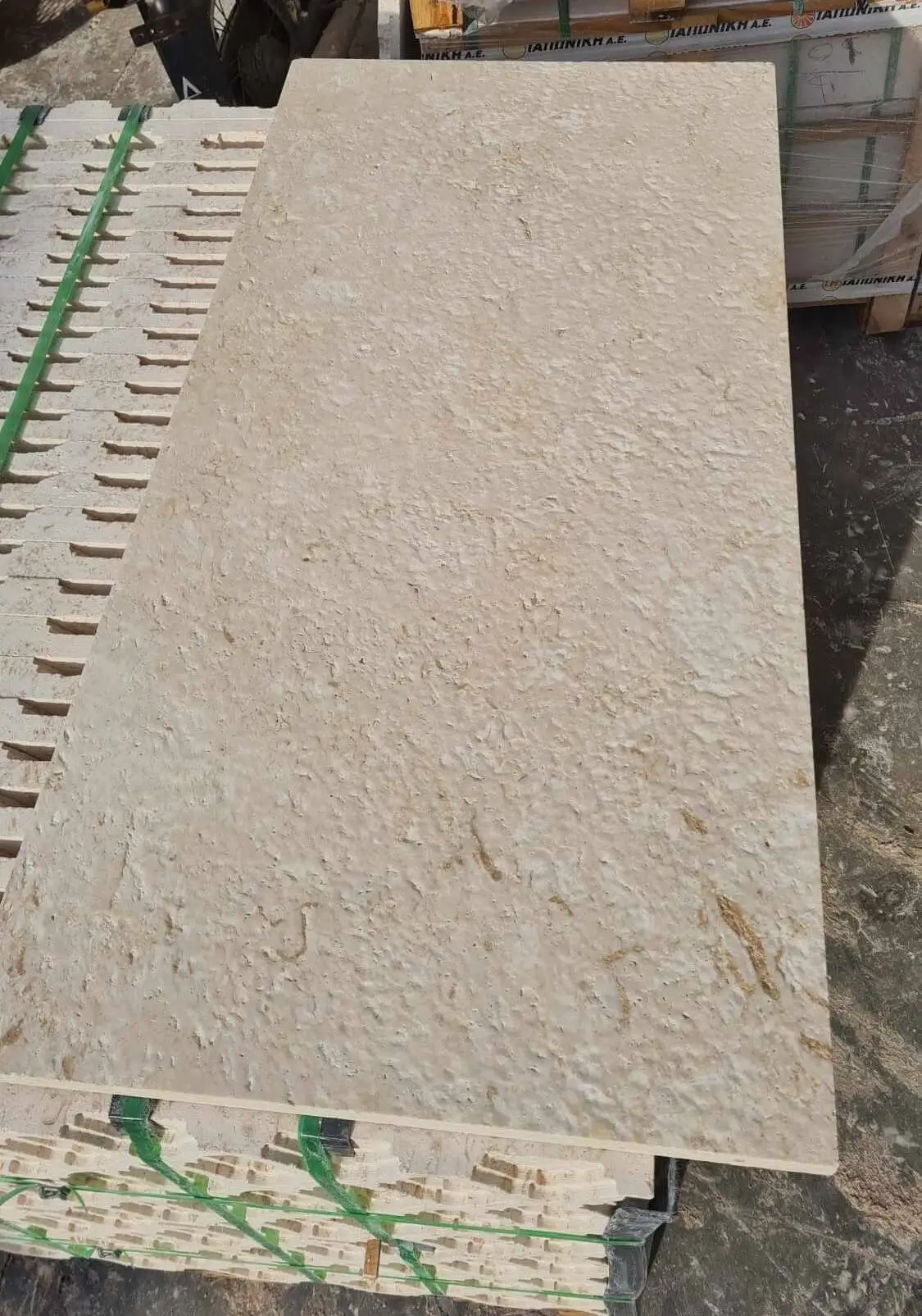 Close-up of a large, textured, beige natural stone slab with a rough surface.