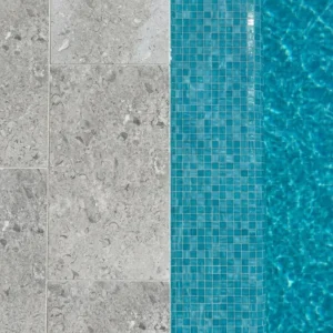 Direct overhead close-up of light grey stone pavers with visible fossil inclusions forming a pool edge next to bright teal mosaic tiles and blue water.