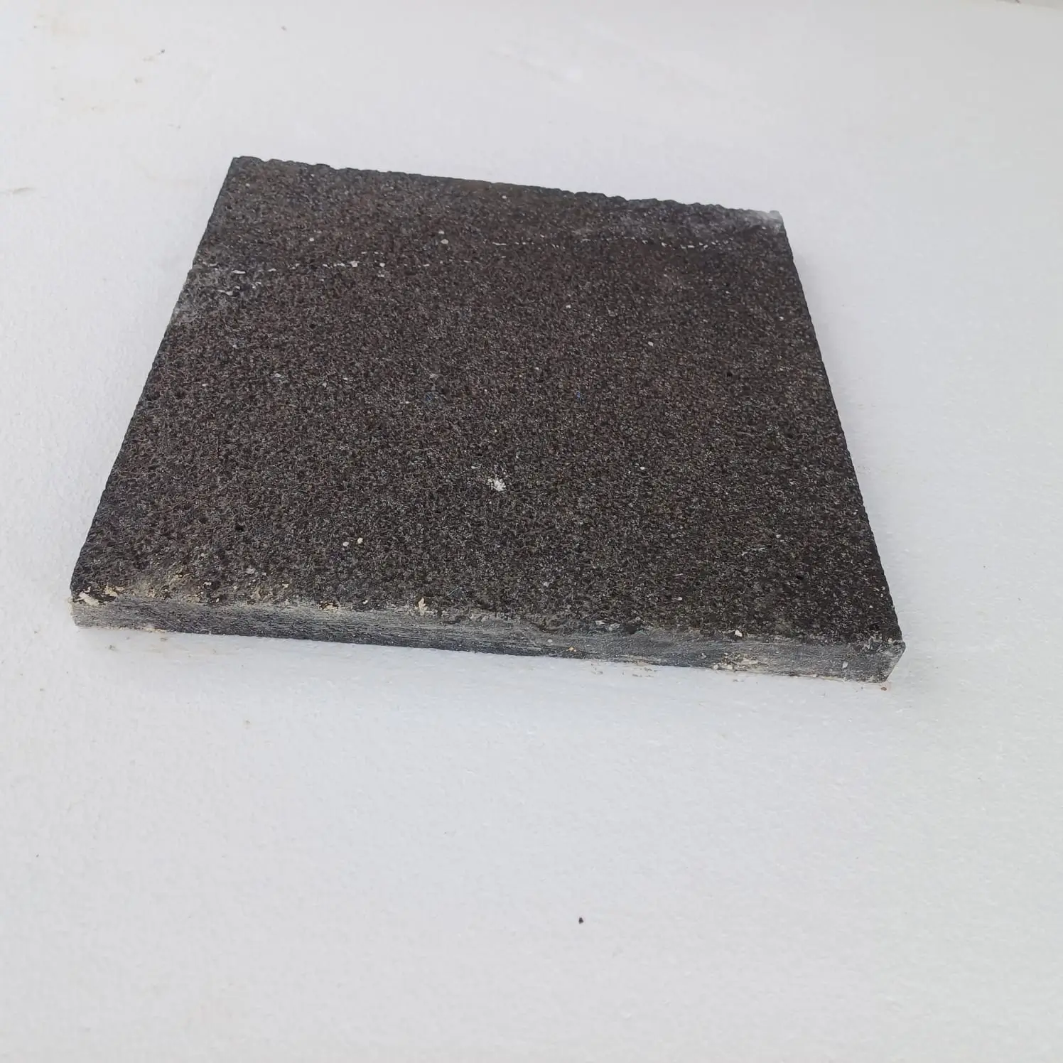 Dark Textured Stone Paver Absolute black granite 12x12 issues detail — close-up of a dark basalt paver with a textured surface and rough edges.