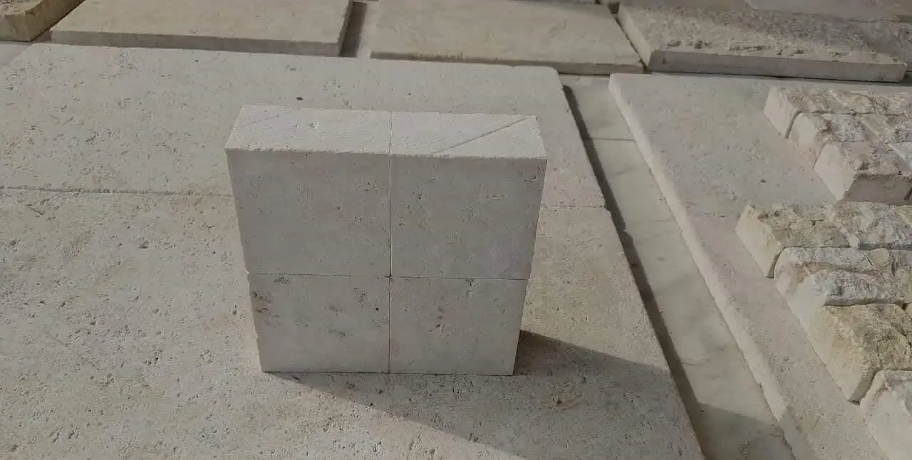 Four light-colored rectangular limestone blocks stacked on a textured surface.