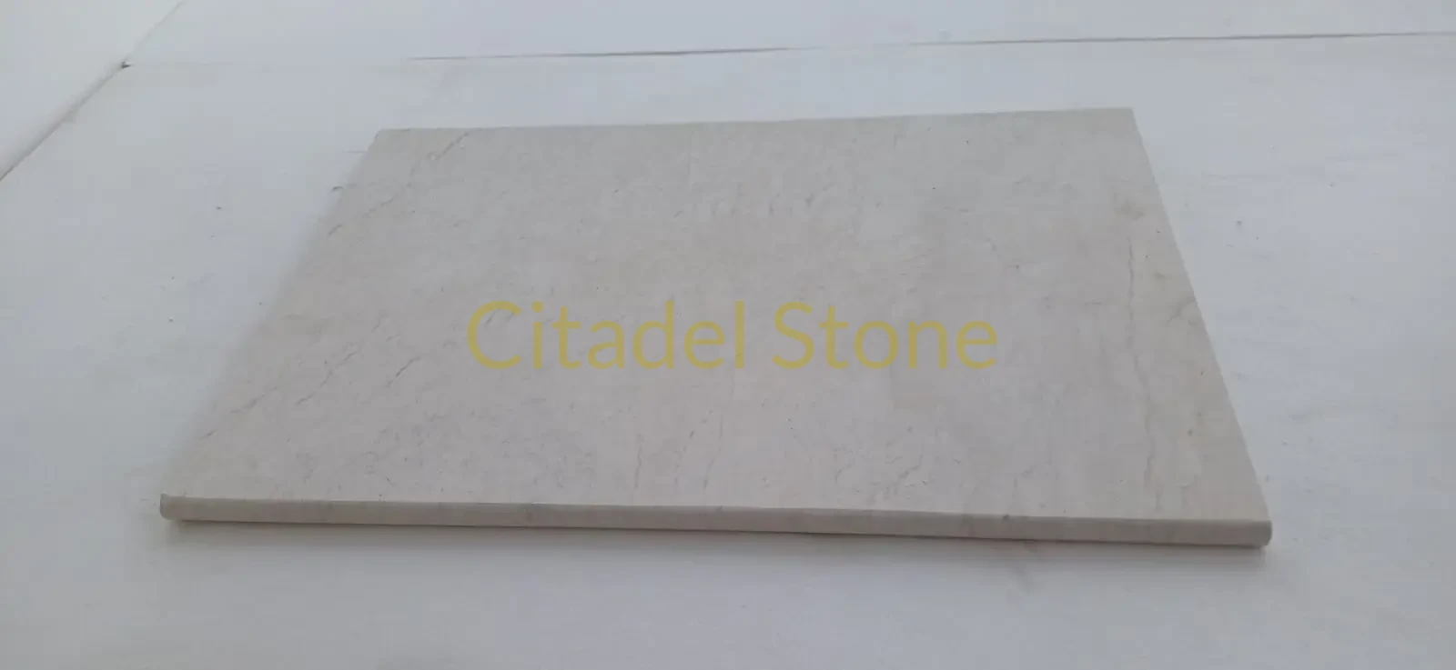 Natural stone garden wall up close — close-up of a smooth beige marble slab with subtle veining on its surface.