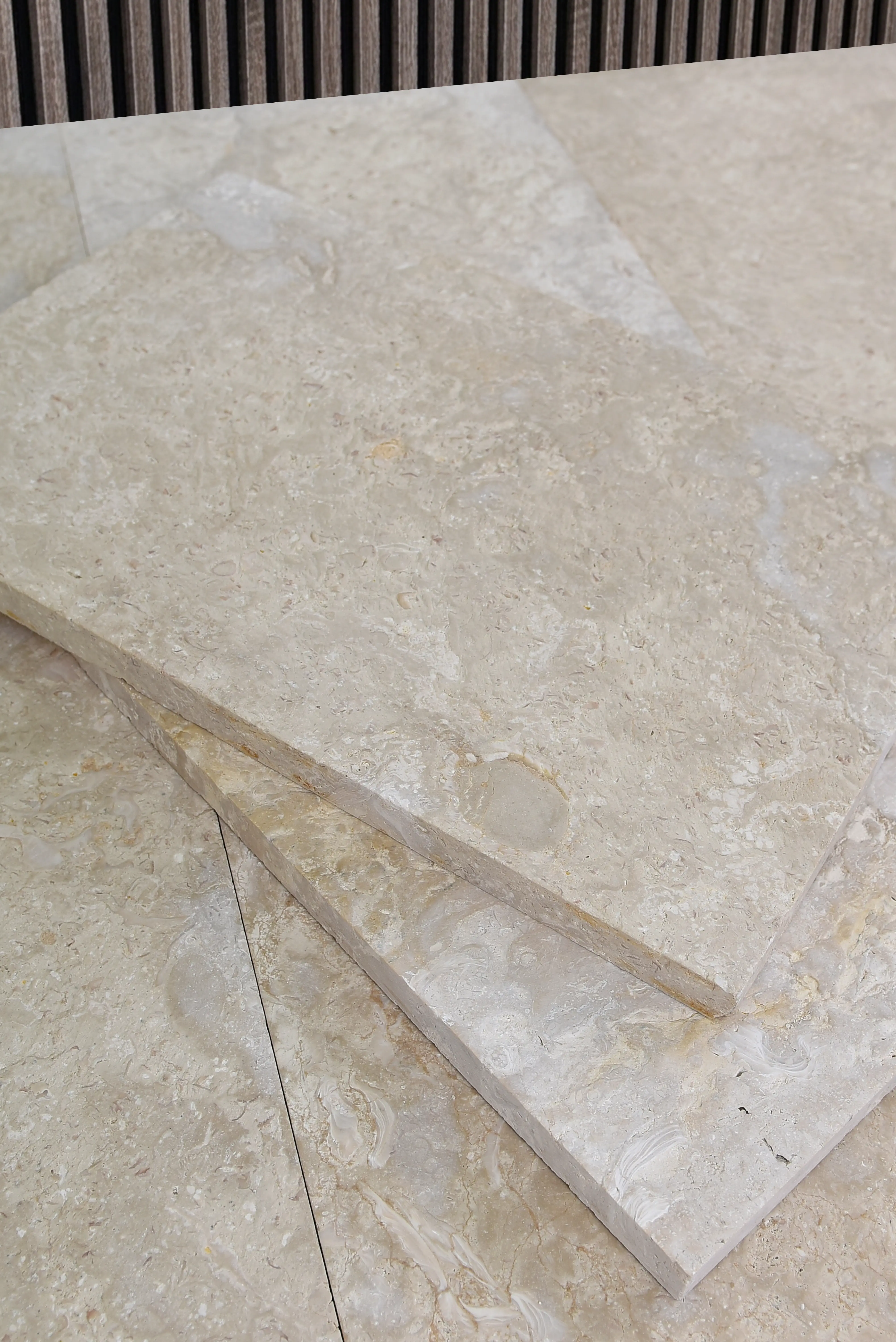 Close-up view of beige limestone slab texture with subtle veining and variations, pictured for river rock vs volcanic rock.