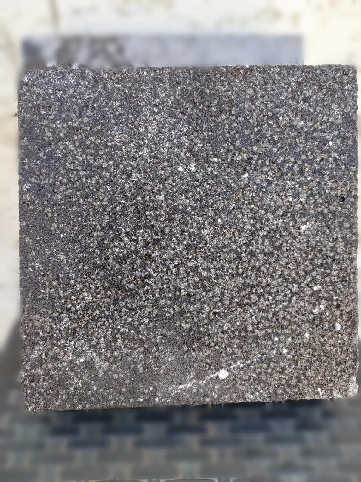 Close-up view of a dark granite block with a textured, speckled surface, a reference for granite curbing suppliers.