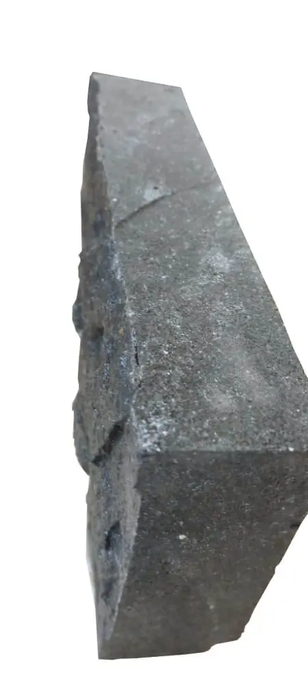 A dark, rough-textured stone block fragment with visible fissures, an example for round paver stones.