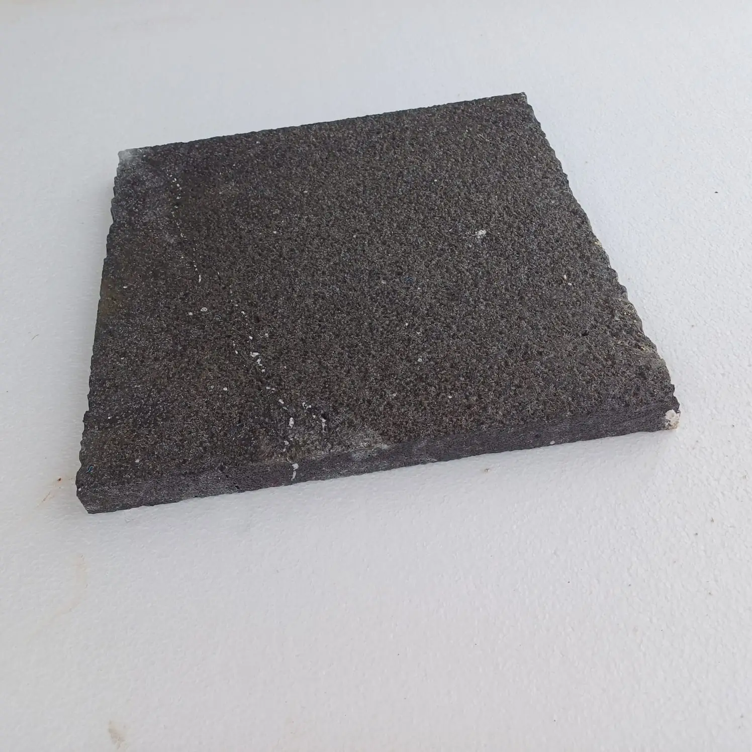 Dark textured basalt stone slab with visible mineral inclusions and rough edges, relevant to bluestone patio.