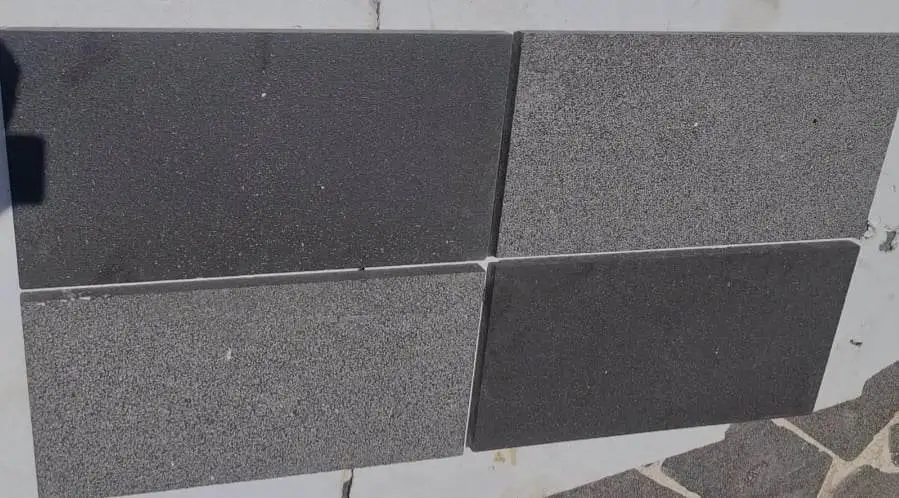 Close-up of four dark grey granite pavers showing contrasting textures and tones, relevant to flat stone for landscaping guide.