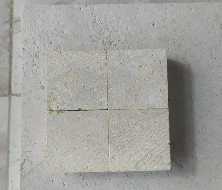 Four light-colored sandstone tiles arranged in a square pattern on a textured surface, relevant to stone window sills vs alternatives.