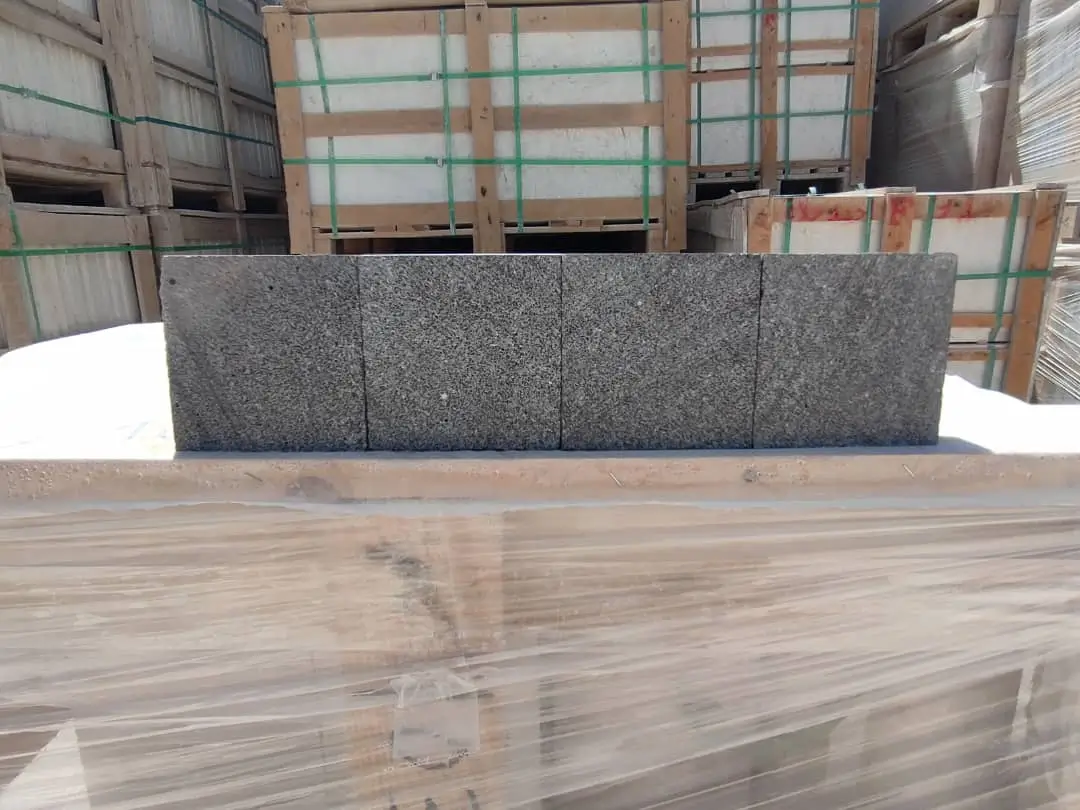 Close-up view of dark grey granite blocks stacked neatly for sale, an example for granite paver maintenance.