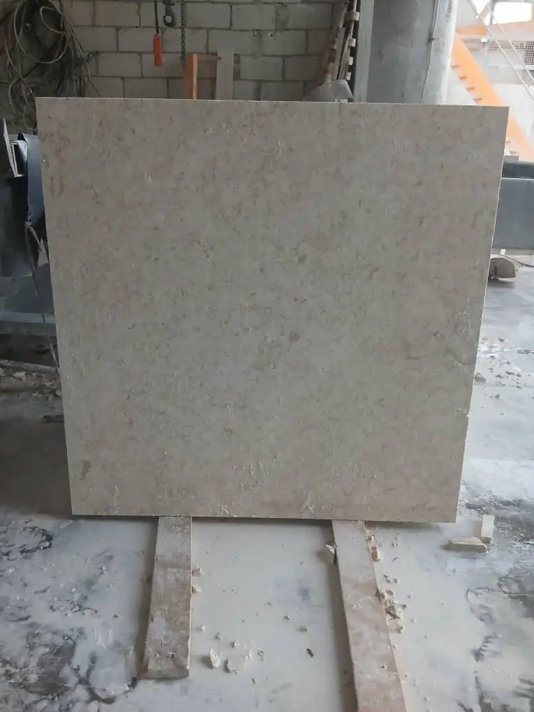 A large square slab of limestone with natural variations is supported by wooden planks, shown for travertine tile pattern ideas.
