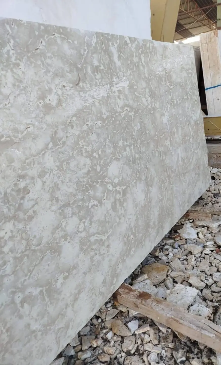 Close-up texture of light beige marble slab showing intricate veining patterns and variations, an example for tumbled travertine tile guide.