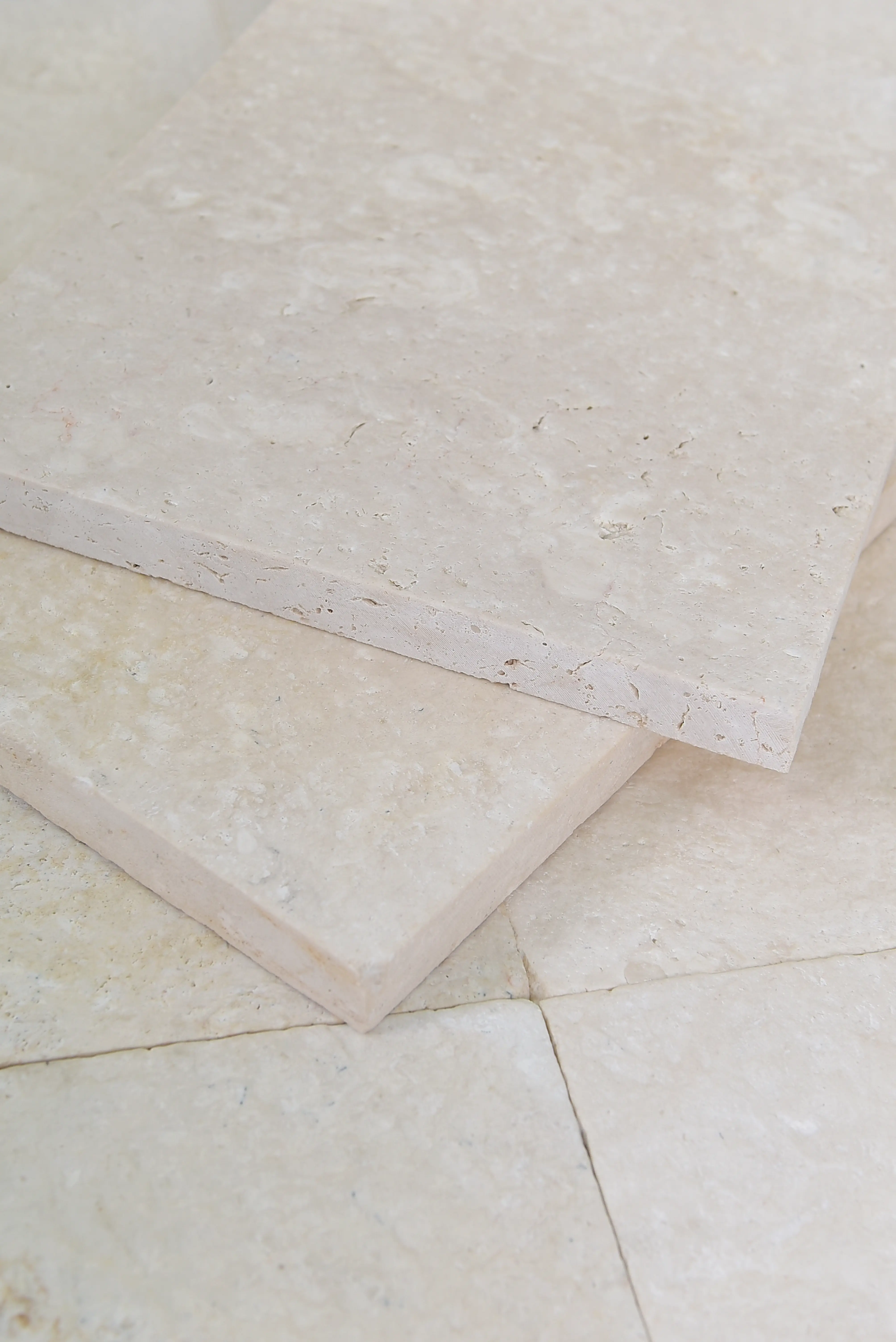 Close-up of light beige travertine floor tiles showing textured surface detail, pictured for modern white travertine pool deck.