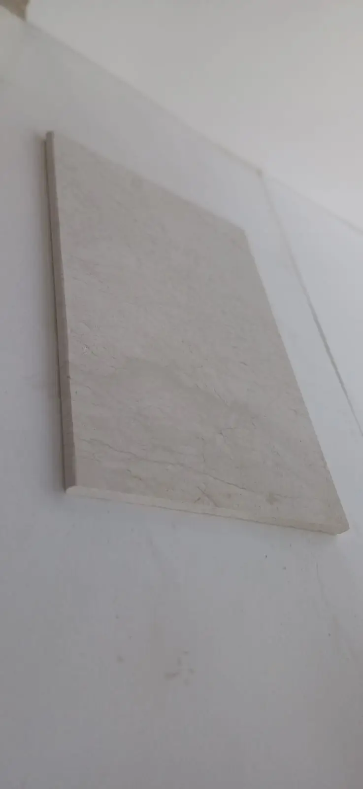 Close-up of light colored textured stone tile showcasing subtle veining patterns, relevant to granite slab size guide.